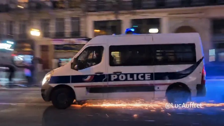 Policajná dodávka prechádza cez iskry z petárd na nočnej ulici v Paríži